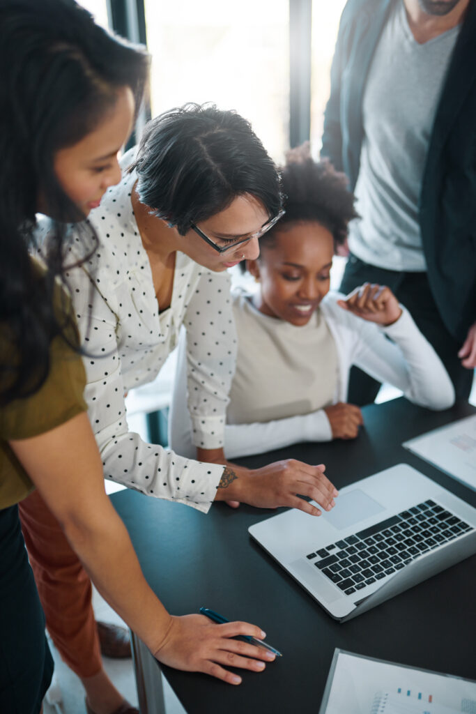 Cropped shot of a group of businesspeople gathered around a laptop in the office.